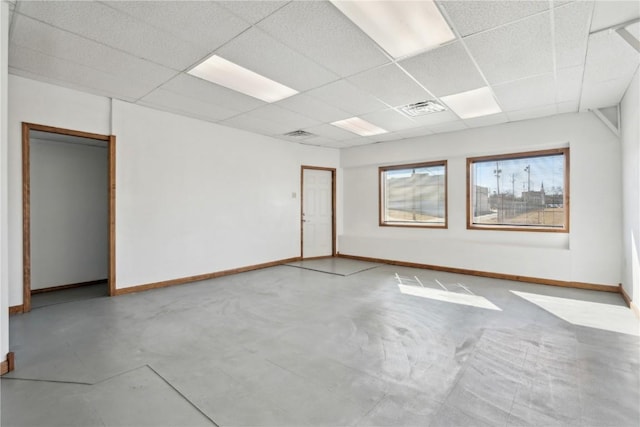 unfurnished room with concrete flooring, a paneled ceiling, visible vents, and baseboards