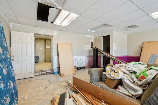 miscellaneous room with concrete flooring, a paneled ceiling, and visible vents