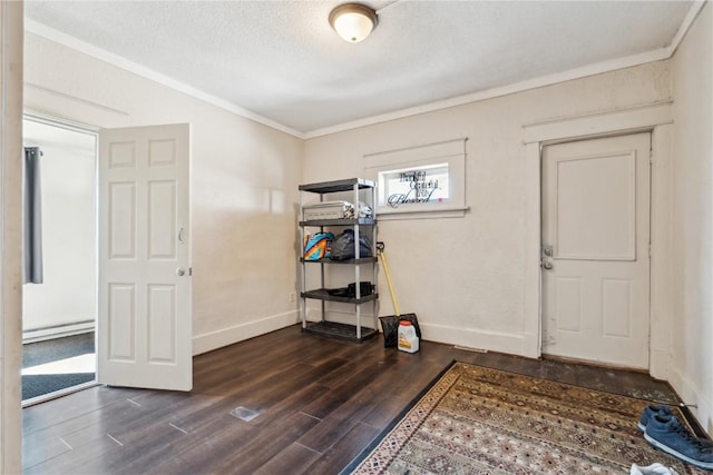 entrance foyer featuring a textured ceiling, a baseboard heating unit, baseboards, ornamental molding, and dark wood finished floors