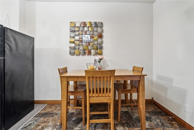 dining space with stone finish flooring and baseboards