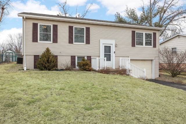 bi-level home featuring an attached garage, brick siding, and a front yard