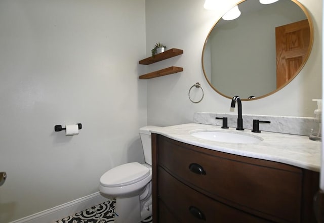 half bathroom featuring baseboards, vanity, and toilet