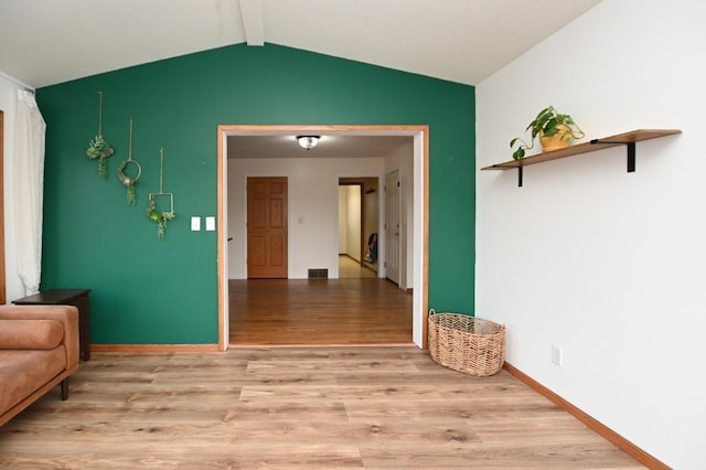 interior space featuring lofted ceiling with beams, light wood finished floors, visible vents, and baseboards