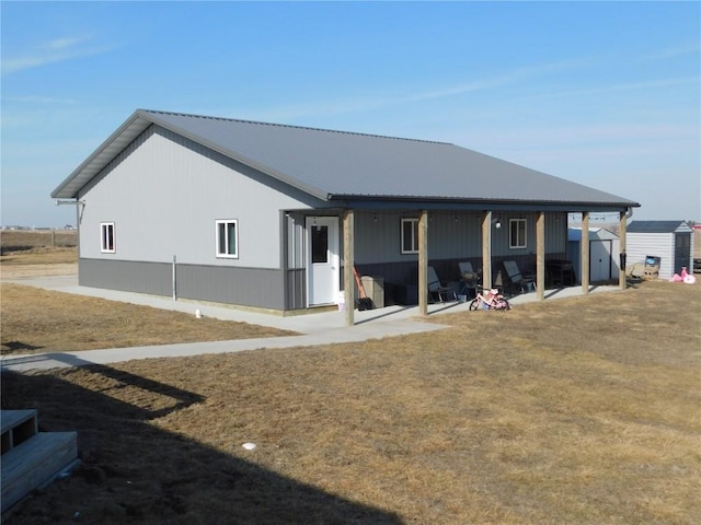 954 Monroe Ave, Tipton, IA 52772 - back of property featuring a storage shed, an outbuilding, metal roof, and a patio area