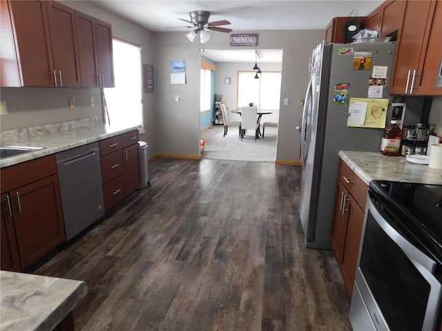 954 Monroe Ave, Tipton, IA 52772 - kitchen featuring appliances with stainless steel finishes, ceiling fan, dark wood-style flooring, baseboards, and brown cabinetry
