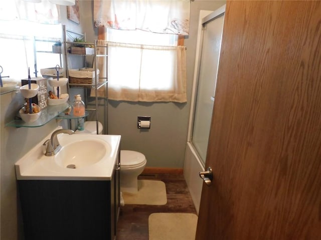 954 Monroe Ave, Tipton, IA 52772 - full bath featuring toilet, vanity, wood finished floors, baseboards, and enclosed tub / shower combo