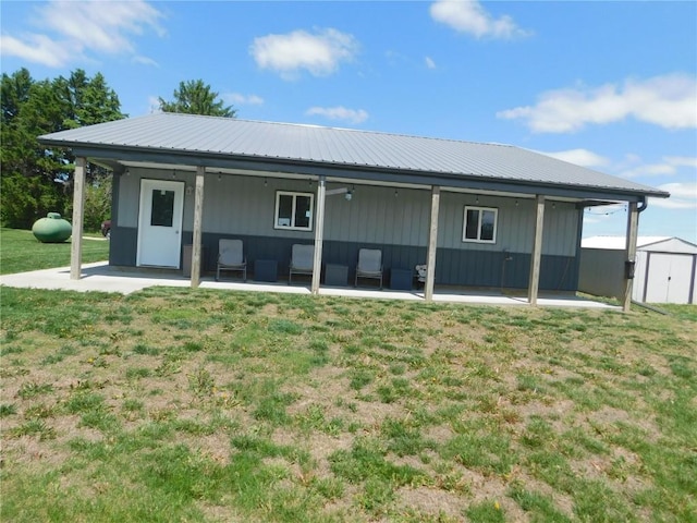 954 Monroe Ave, Tipton, IA 52772 - rear view of property featuring a lawn, a patio area, metal roof, a shed, and an outdoor structure