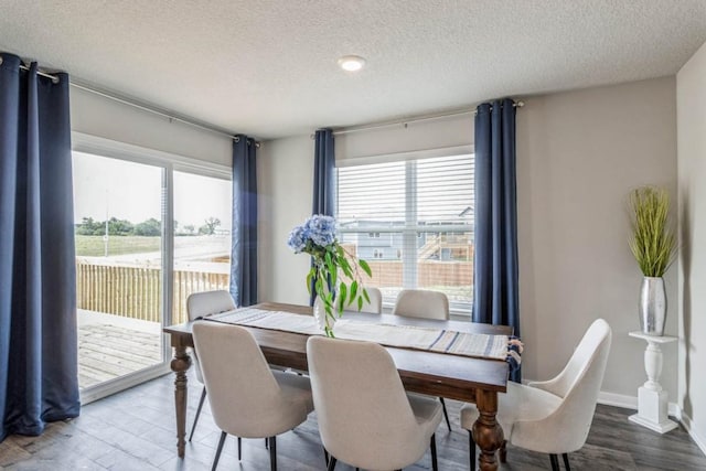 dining area with a textured ceiling, baseboards, and wood finished floors