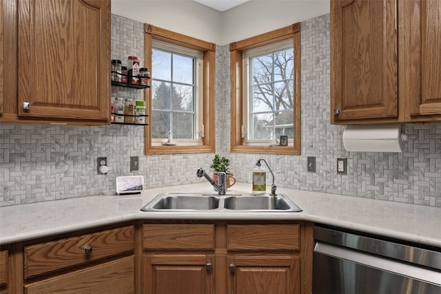 kitchen with a sink, decorative backsplash, light countertops, and stainless steel dishwasher