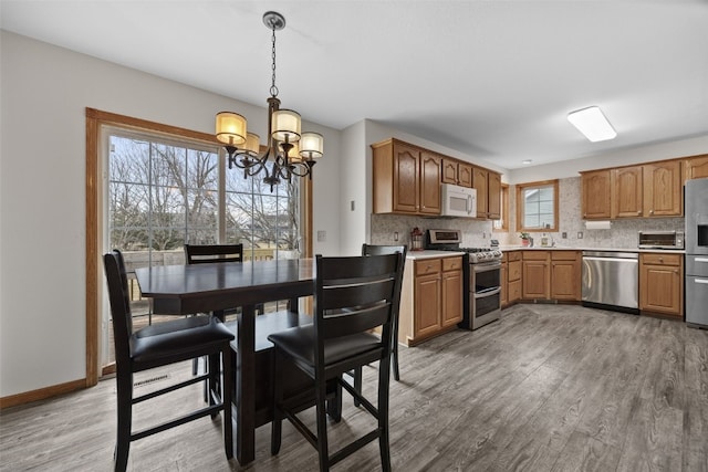 kitchen with light wood-style floors, appliances with stainless steel finishes, decorative backsplash, and light countertops