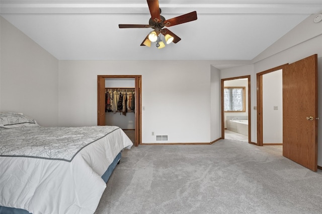 bedroom with lofted ceiling, light carpet, visible vents, and a walk in closet