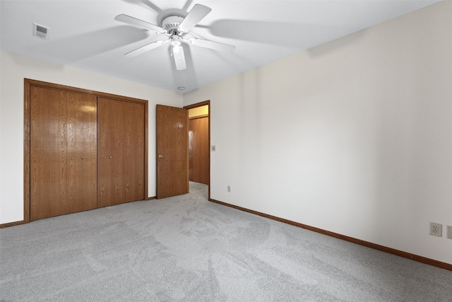 unfurnished bedroom featuring light carpet, a closet, visible vents, and baseboards