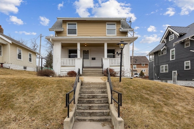 view of front facade with a porch, a front yard, and stairway