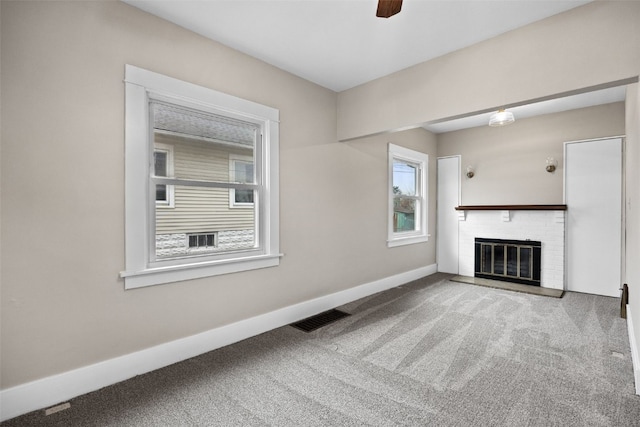 unfurnished living room with a ceiling fan, visible vents, baseboards, a brick fireplace, and carpet