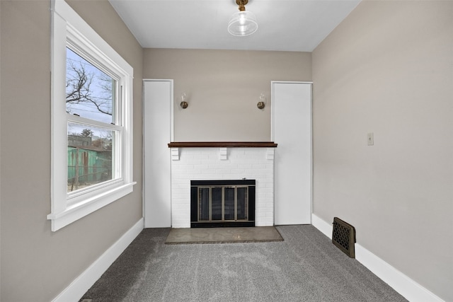 unfurnished living room featuring a brick fireplace, carpet flooring, visible vents, and baseboards