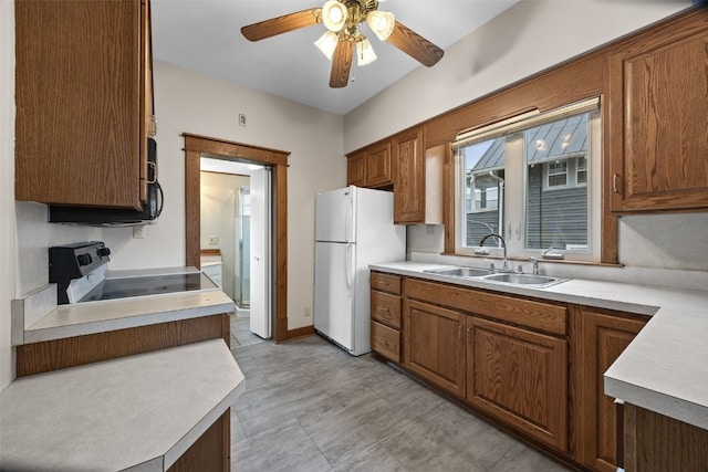 kitchen with electric range oven, light countertops, a sink, and freestanding refrigerator