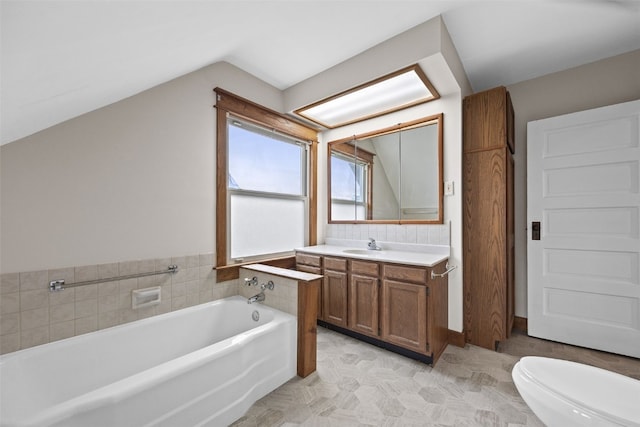 bathroom with lofted ceiling, toilet, a garden tub, and vanity