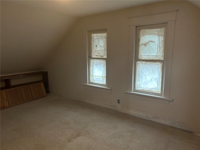 bonus room with lofted ceiling, baseboards, and light colored carpet