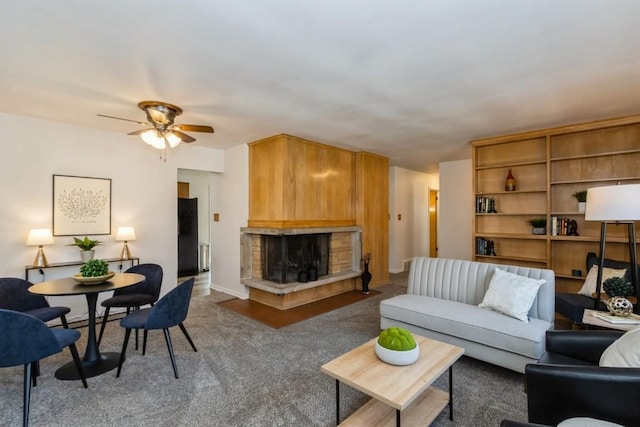 carpeted living area featuring a fireplace with raised hearth, a ceiling fan, and baseboards