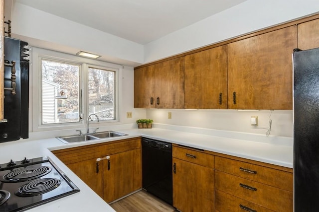 kitchen featuring light countertops, a sink, and black appliances