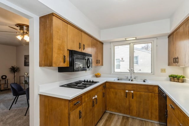 kitchen with black appliances, brown cabinetry, and a sink