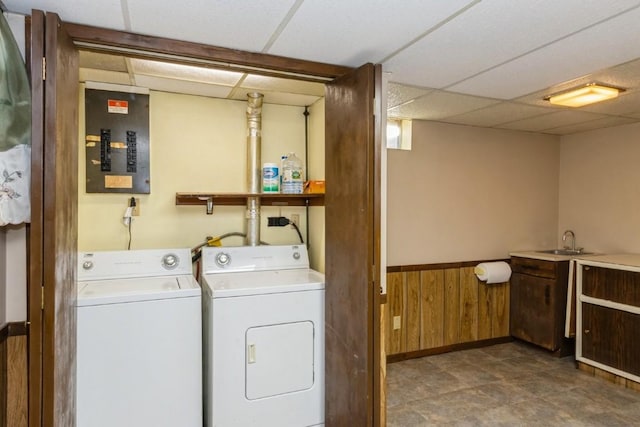 clothes washing area with a wainscoted wall, washing machine and dryer, wood walls, laundry area, and electric panel