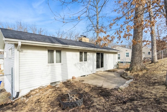 rear view of house featuring a patio, a chimney, and fence