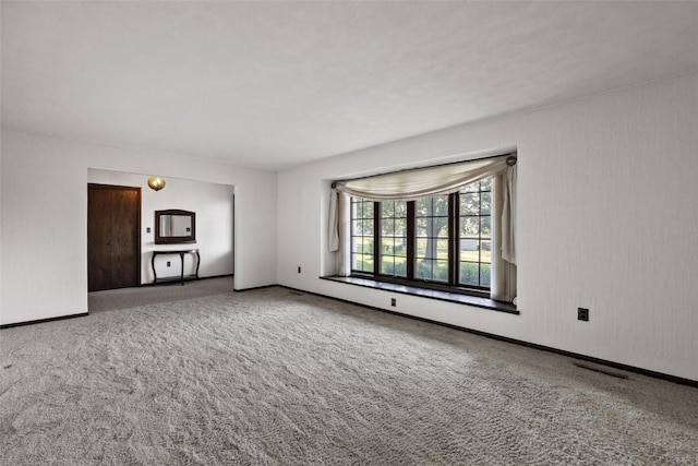 unfurnished living room with carpet floors, visible vents, and baseboards