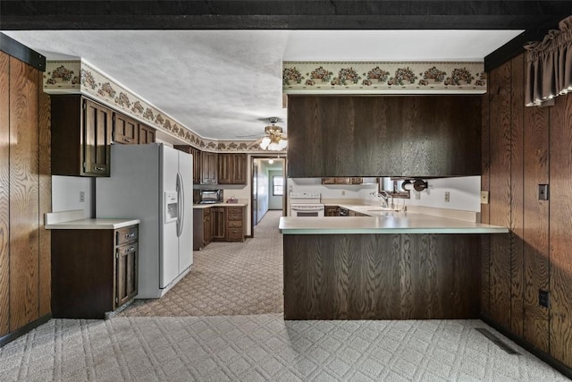 kitchen featuring light countertops, white appliances, a peninsula, and wooden walls