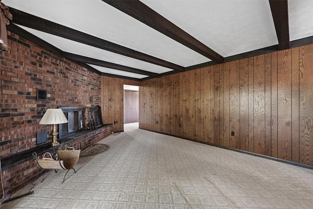 unfurnished living room featuring a brick fireplace, beam ceiling, and wood walls