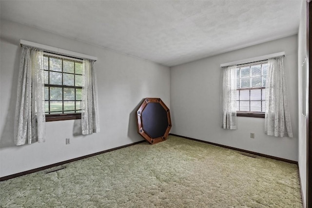 spare room featuring baseboards, carpet flooring, and a healthy amount of sunlight