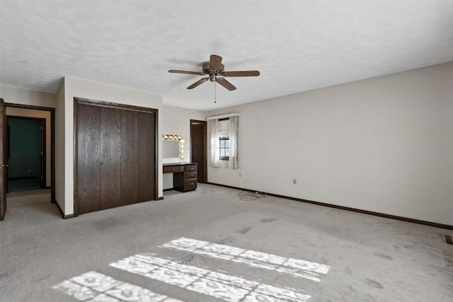 unfurnished bedroom featuring light carpet, a closet, a ceiling fan, and baseboards