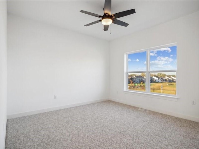 carpeted spare room with ceiling fan and baseboards