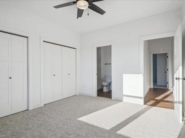 bedroom featuring ceiling fan, connected bathroom, carpet floors, baseboards, and multiple closets