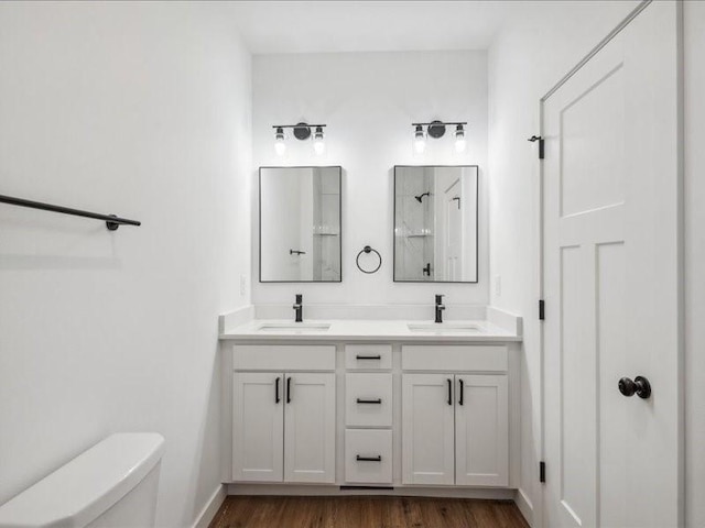 bathroom featuring toilet, walk in shower, a sink, and wood finished floors