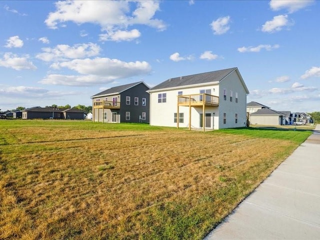 back of house featuring a balcony and a lawn