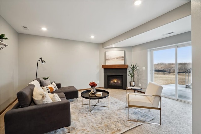 carpeted living area with a glass covered fireplace, visible vents, and recessed lighting