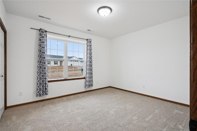 spare room featuring carpet flooring, visible vents, and baseboards