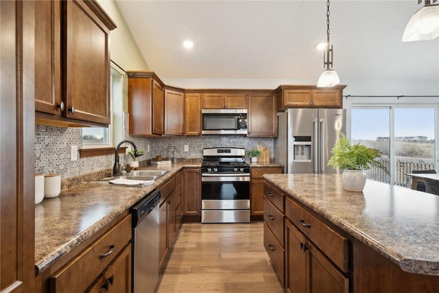 kitchen with light wood finished floors, appliances with stainless steel finishes, a sink, and tasteful backsplash