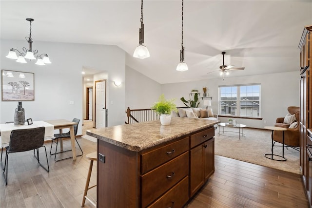 kitchen featuring lofted ceiling, a kitchen island, open floor plan, and decorative light fixtures