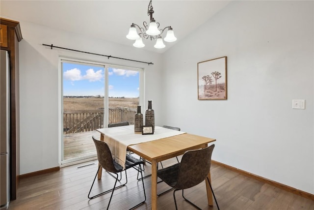 dining space featuring baseboards, vaulted ceiling, an inviting chandelier, and wood finished floors