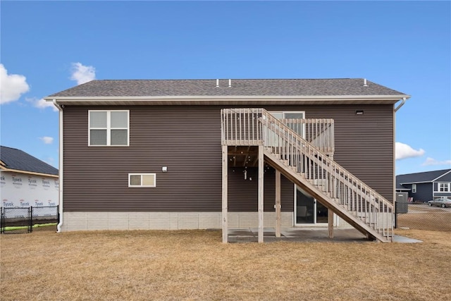 rear view of property with a lawn, fence, a wooden deck, and stairs