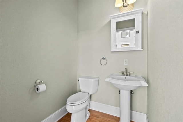 bathroom featuring a sink, wood finished floors, toilet, and baseboards