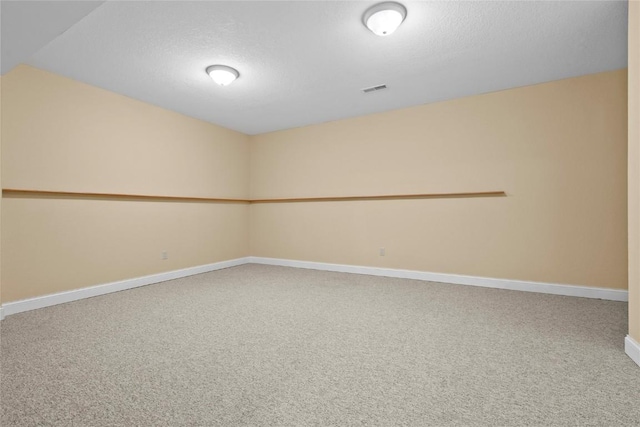 empty room featuring carpet floors, visible vents, a textured ceiling, and baseboards