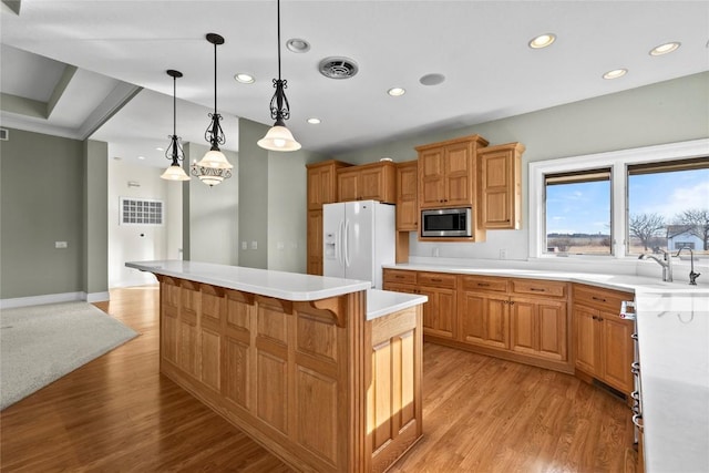 kitchen with light wood finished floors, visible vents, stainless steel microwave, white fridge with ice dispenser, and a sink