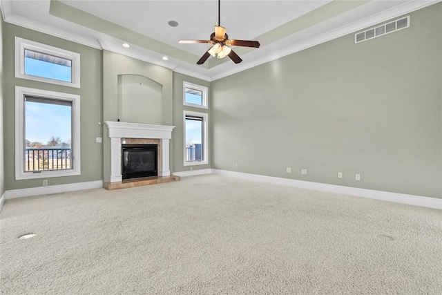 unfurnished living room featuring a tray ceiling, a premium fireplace, carpet, and visible vents