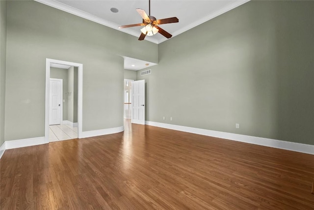 spare room featuring visible vents, crown molding, baseboards, and wood finished floors