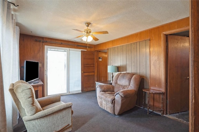 living area with wood walls, carpet flooring, ceiling fan, and a textured ceiling