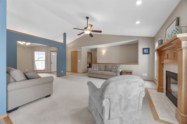 living area with lofted ceiling, a tile fireplace, light colored carpet, ceiling fan with notable chandelier, and baseboards