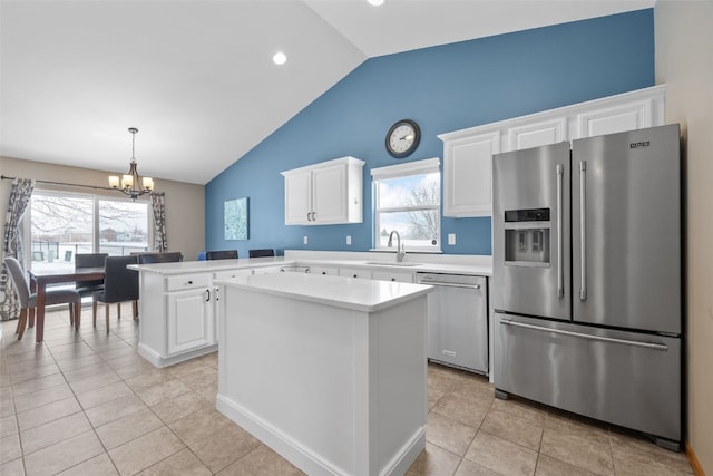 kitchen with a peninsula, a sink, white cabinets, light countertops, and appliances with stainless steel finishes